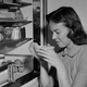 Woman sniffing moldy food from fridge